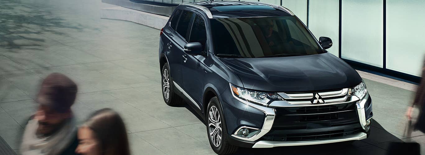 Black [mitsubishi model] stopped as pedestrians cross the street