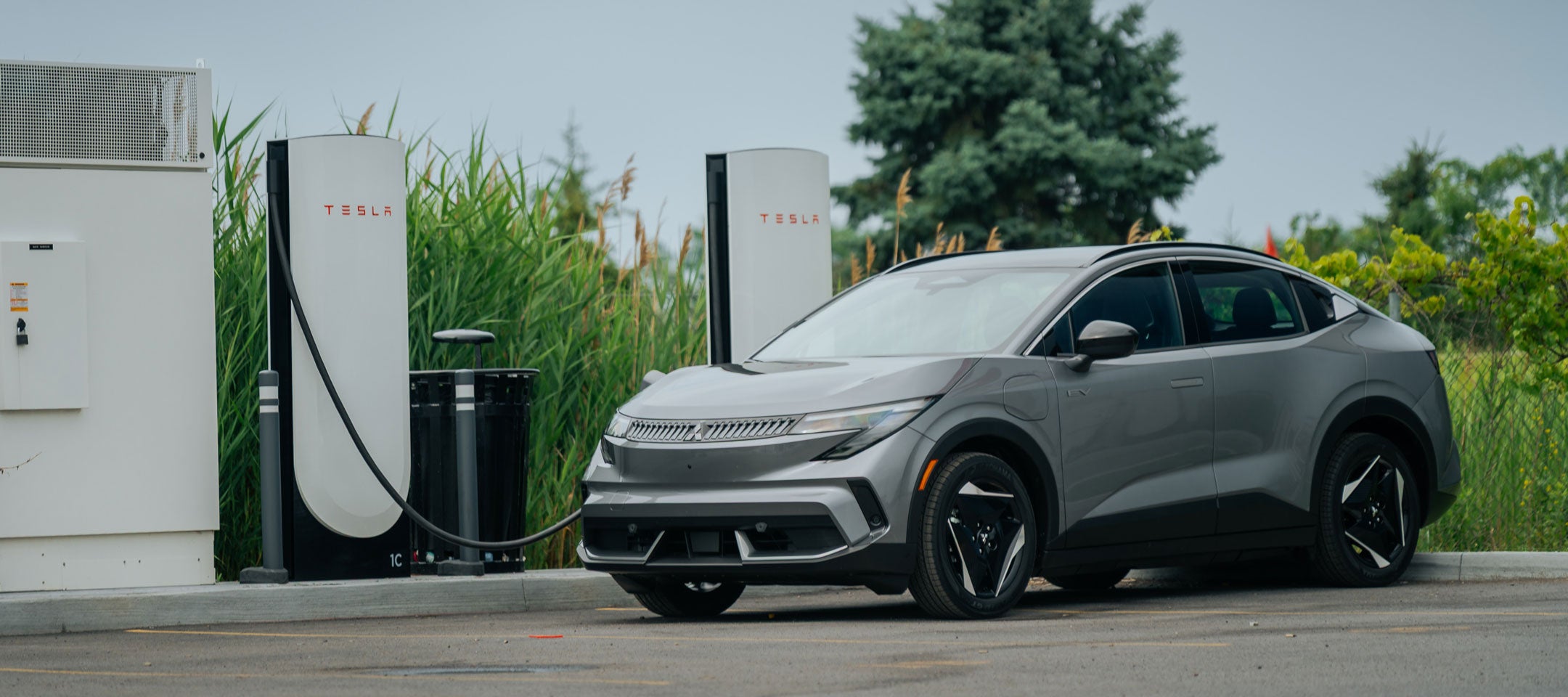 NACS fast charging for the 2027 Mitsubishi Eclipse Sportback 2027 Mitsubishi Eclipse Sportback EV in front of NACS fast charging stations