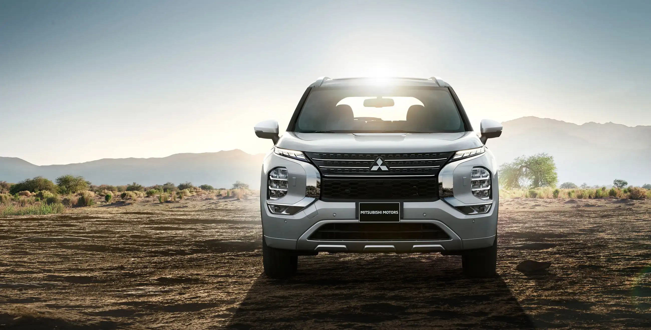 Vue de face du Mitsubishi Outlander PHEV 2024 avec le lever du soleil derrière