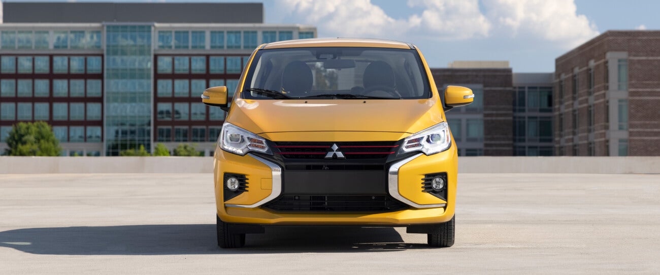 Front profile of a sand yellow metallic 2024 Mitsubishi Mirage parked in a parking lot