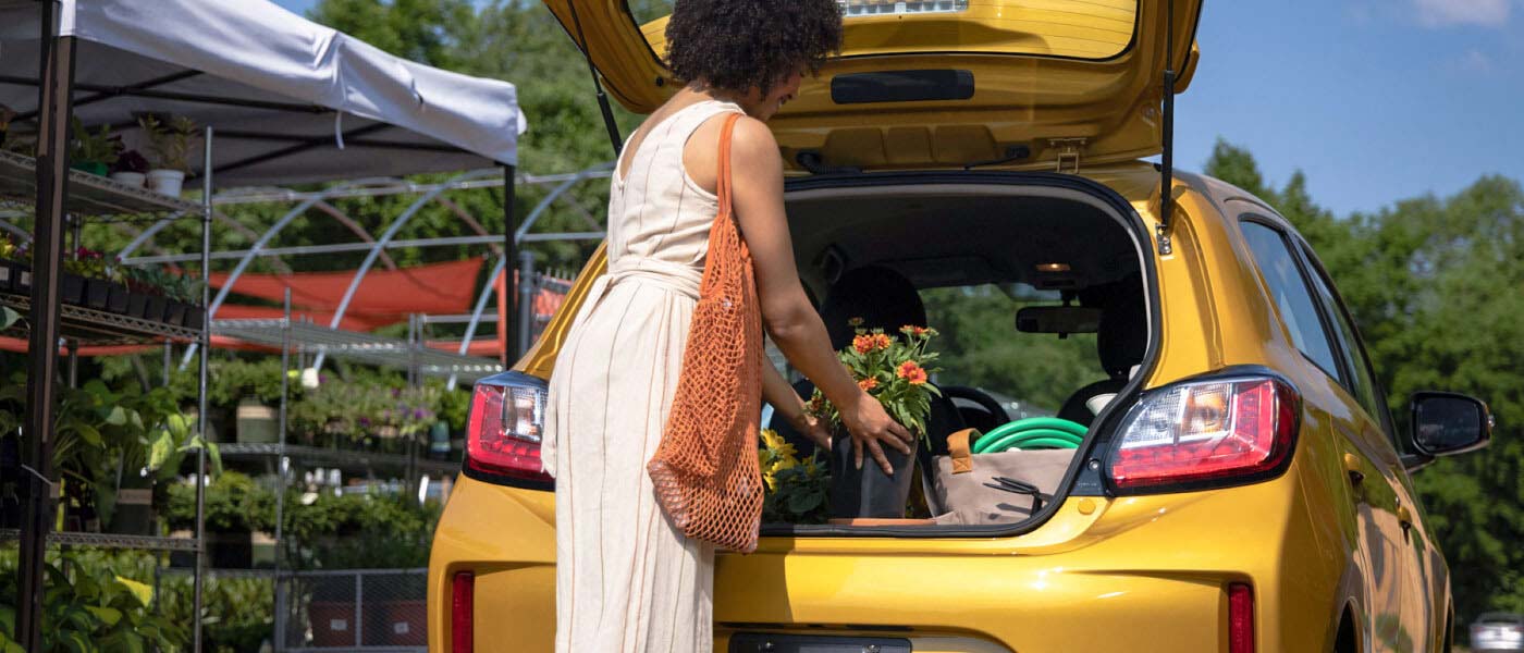 Woman placing flower pot and other items in the spacious cargo area in the 2023 Mitsubishi Mirage
